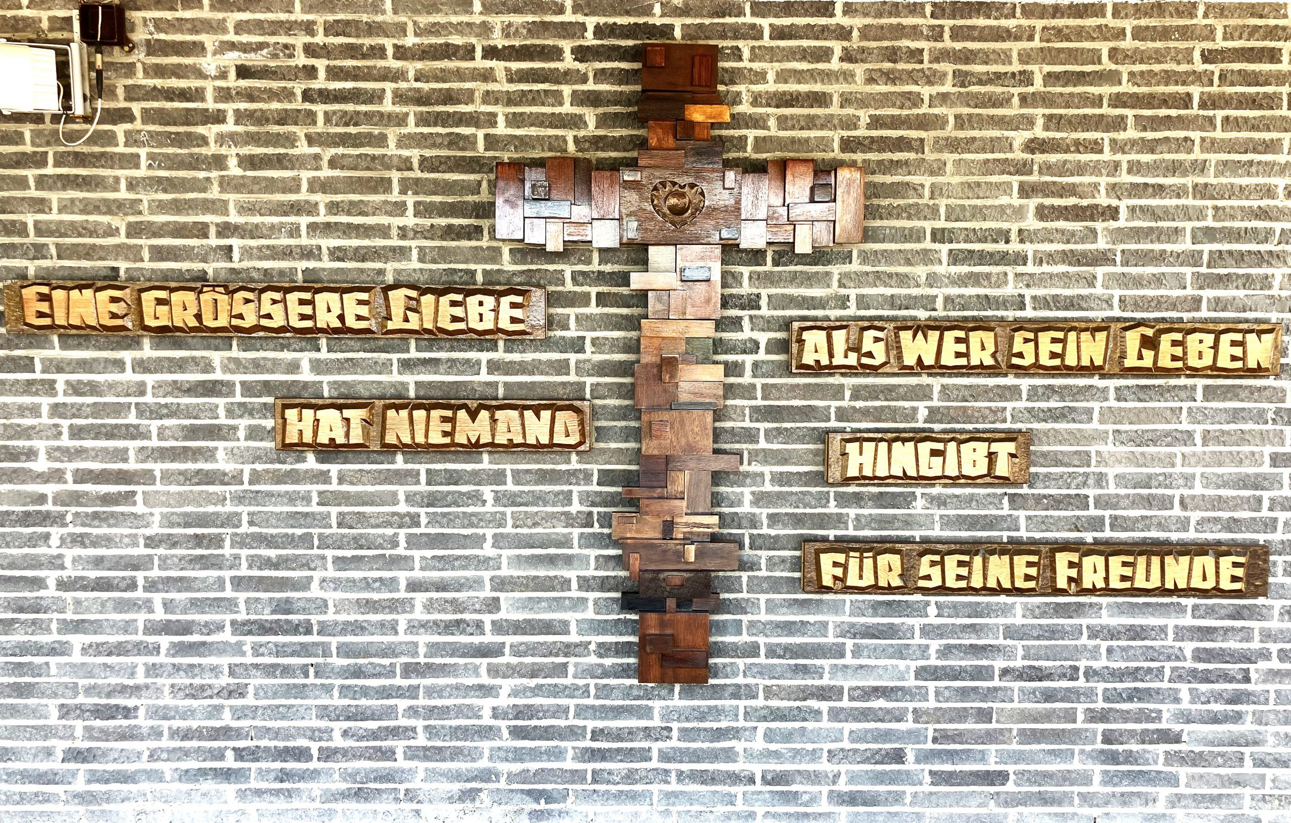 Inschrift und Kreuz an der Friedhofshalle saniert